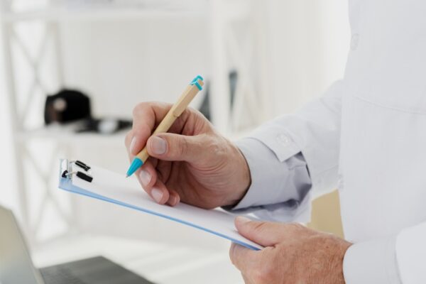 close-up-doctor-writing-clipboard Doctor Writing on Clipboard